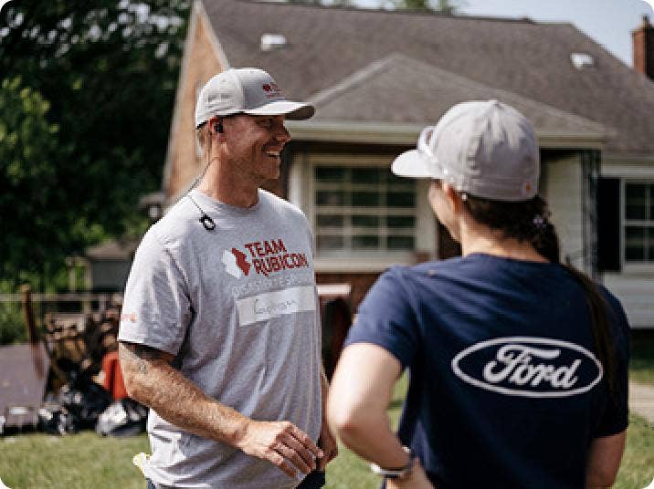 Two people talking in front of a house